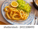 Small photo of Dish of tasty fried squids in a batter of tempera flour served with salad and lemon