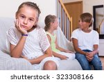 Small photo of Offended little girl is jealous sister of teenage stepbrother in the living room