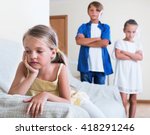 Small photo of Upset morose little girl is jealous sister of stepbrother indoors