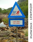 Small photo of Dorgefoss, Norway - June 11, 2017: Sign near the Dorgefoss waterfall, cautioning that hatches of dam on Sira river can be opened without warning.