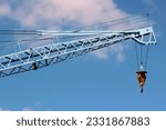 Construction crane arm with hook against blue sky background
