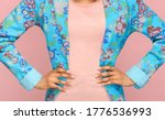 Small photo of Fashion detail of a tailored floral blue jacket on a slender young woman standing with hand on hips in a close up on her midriff