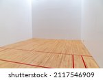 Inside a raquetball court, with red markings, white walls and wood floors
