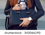 Trendy young girl in black leather jacket holding big black handbag street background .  Fashion accessories