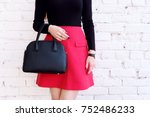 Beautiful fashion outfit, red skirt and black big leather bag in hand of girl . Stylish accessory