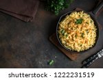 Mac and cheese, american style macaroni pasta with cheesy sauce and crunchy breadcrumbs topping on dark rustic table, copy space top view