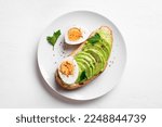 Small photo of Avocado toast with hard boiled eggs on white background, top view. Toasted bread with avocado and egg for healthy breakfast.