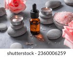 Small photo of Bottle of essential rose oil and rose flowers, candles, zen stones ans sea salt. Spa and aromatherapy concept.
