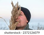 Winter portrait of handsome man in hoarfrosted grass. Winter season. snowy reeds. Soft blue sky background.