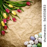 Small photo of astern egg, tulips on brown crumpled wrapping paper, top view
