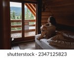 Young woman sitting on a bed in ...
