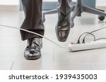 Small photo of Close up of a businessman legs stumbling with an electrical cord at office