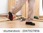 Small photo of Close up of a carpenter legs stumbling with an electrical cord at home