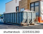 A big, heavy-duty dumpster next to a new fast food restaurant under construction.