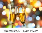 two glasses of champagne toasting against bokeh lights background