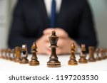 Businessman with clasped hands planning strategy with chess figures on table. Strategy, leadership and teamwork concept.