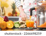 Small photo of Squeezing carrot juice with juicer healthy citrus fruits in background. Intake vitamins detox, healthy diet and living concept.