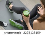 Small photo of Women's hands tying sport shoes on a gray workout mat. With smoothie for detox in background. Healthy living, dieting lifestyle.