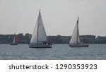 Small photo of Low angle photo of two sloops racing each other on quiet lake following closely these are small sailing boats with a single mast and a fore and aft rig and one head-sail vessels