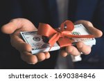 Concept, money as a gift, win or bonus. businessman takes or gives pile of 100 dollar bills tied with red ribbon with bow.