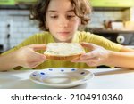 Small photo of Teenage girl eating snack of toaster bread with cheese or butter. bite toasted toast bread. want to eat buttered toaster bread. young woman looks at toaster bread spread with melted cheese