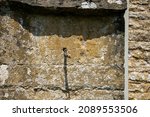Small photo of Mass dial on the wall of St Nicholas Church, Asthall, showing the gnomon casting a shadow