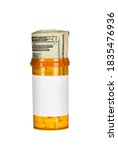 Small photo of A pill bottle with pills and a roll of cash inside to infer the rising costs of prescription drugs.