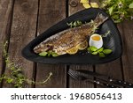 Grilled rainbow trout with lemon and herbs on wooden table