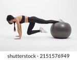 young sportswoman doing basic plank exercise with fitness ball isolated on white background