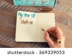 Retro effect and toned image of a woman hand writing a note with a fountain pen on a notebook. Handwritten text MY NEW LIFE CHAPTER ONE, motivation concept