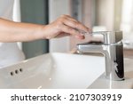 Small photo of Close up Woman open chrome faucet washbasin to washing hands rubbing with soap for corona virus at water tap. Faucet and water drop off. Bathroom interior background with sink basin and water tap.