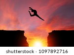Small photo of Silhouette of girl dancer in a split leap over dangerous cliffs with sunset or sunrise background and copy space. Concept of faith, conquering adversity, taking risk; challenge, courage, determination