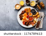 Small photo of Full fry up English breakfast with fried eggs, sausages, bacon, black pudding, beans, toasts and coffee on gray concrete background