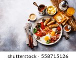 Full English breakfast with fried eggs, sausages, bacon, beans, toasts and coffee on copy space background