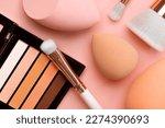 Small photo of Top view of eyeshadow, makeup sponges and makeup brushes over pink background. Beauty and makeup concept