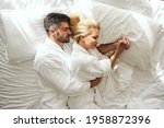 Sleeping in the embrace and intimacy of a loving partner with gentle touches in a bed. A beautiful couple in a luxury hotel fills with positive energy. Romantic sleepy lovely bird, holding hands, hug