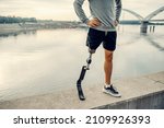 A handicapped sportsman with artificial leg standing at the quay with hands on the hips. Legs on the quay.