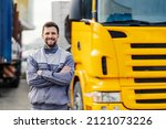 A smiling truck driver posing with trucks.
