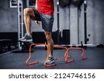 Small photo of Exercises with hurdles. Close-up shot of a man’s legs in sportswear that skips small hurdles. Jumping over obstacles and warming up for training. Healthy lifestyle, strong movement, dynamism