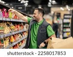 Small photo of A happy stock clerk is arranging groceries on shelves at supermarket.