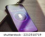 Voice search, speech recognition and sound detect app concept with close up smartphone lying on a black wooden table and sound wave, microphone, voice search text on the screen.