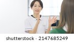 Small photo of Talking middle aged Asian woman with white robe. Medical consultation. Beauty advisor. Counselor.
