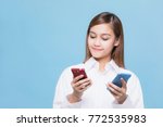 Young woman holding two smart phones.