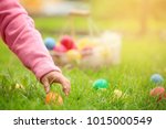 Little girl gathering colorful egg in park. Easter hunt concept