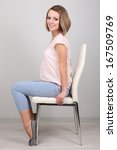 Small photo of Young regnant woman sitting on chair on wall background