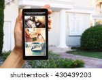 Female hand holding a smartphone on blurred house background. Home security system concept