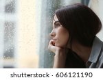 Depressed young woman near window at home, closeup