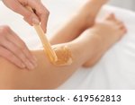 Beautician waxing female legs in spa center