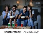 Friends watching TV in evening at home