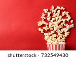 Paper cup with popcorn on color background